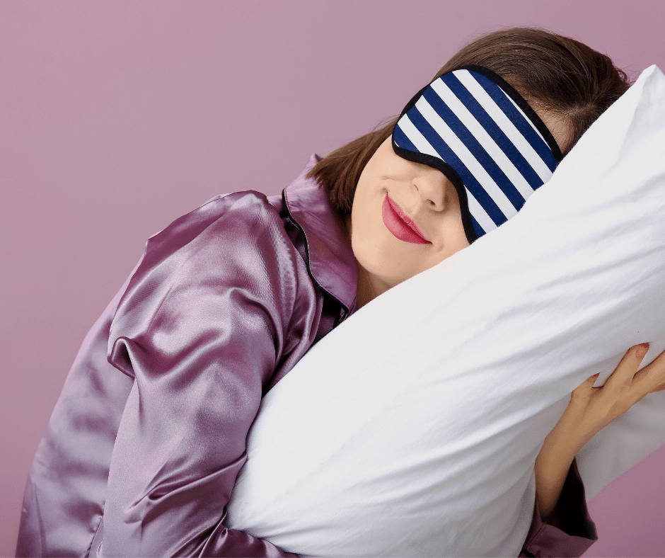 a woman with an eye mask on in pyjama's hugging a pillow case with a silk cover