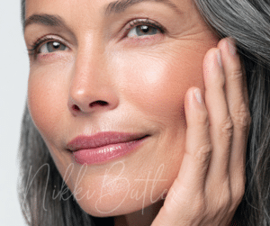 a close up image of a woman's face with her hand on her cheek and greying hair