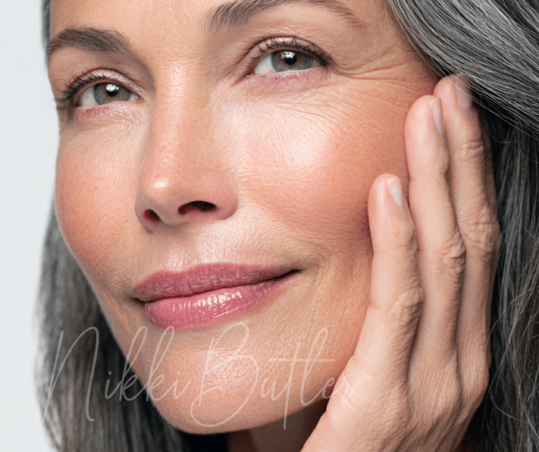a close up image of a woman's face with her hand on her cheek and greying hair